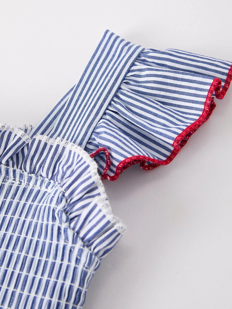 Blue and white striped toddler dress with red trim on a light gray background
