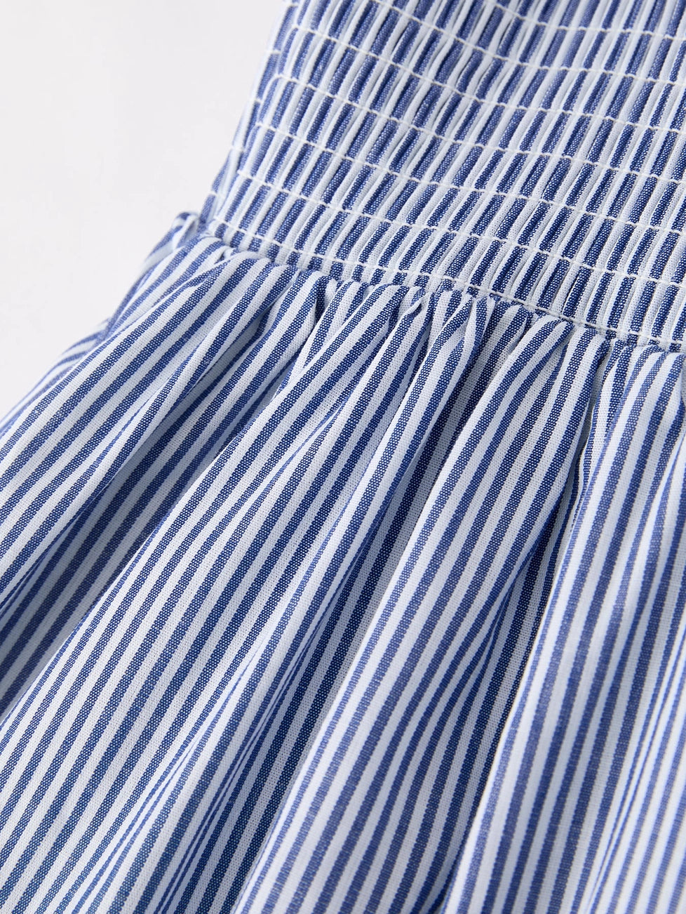 Close-up of a blue and white striped fabric garment, showing a smocked bodice and gathered skirt.