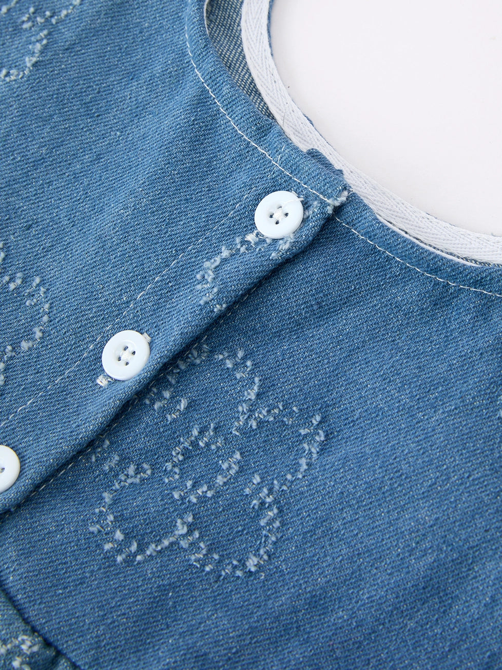 Close-up of a blue denim shirt with white buttons and stitching details.