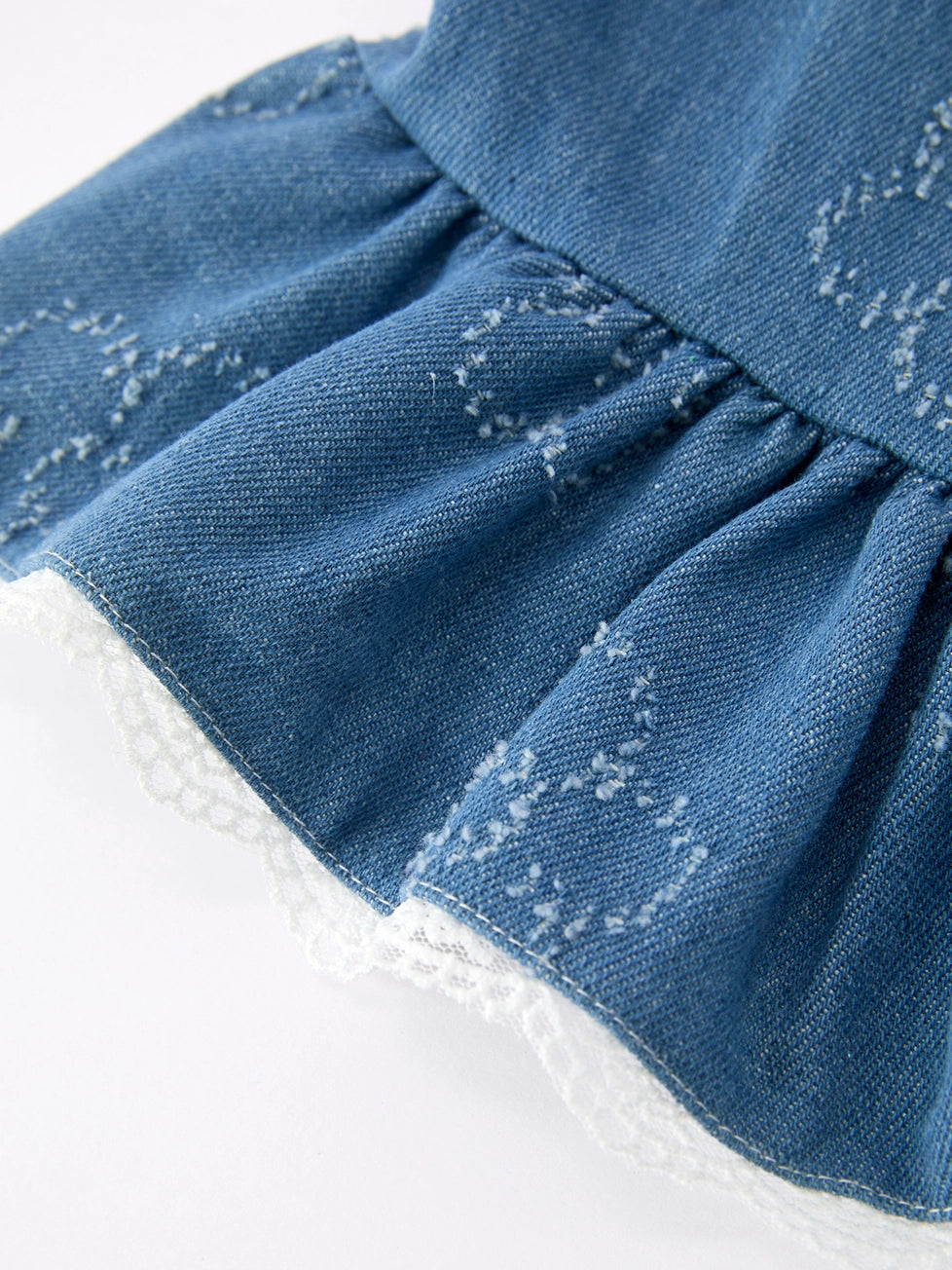 Close-up of a blue denim skirt with white sole shoes on a light gray background